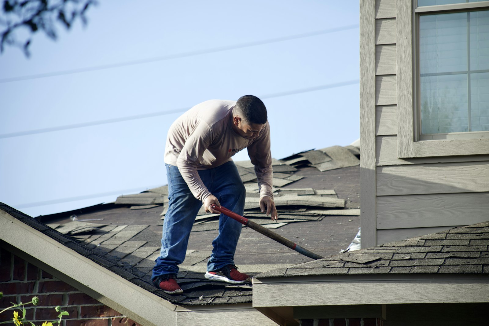 Roofer removing damaged shingles during a repair