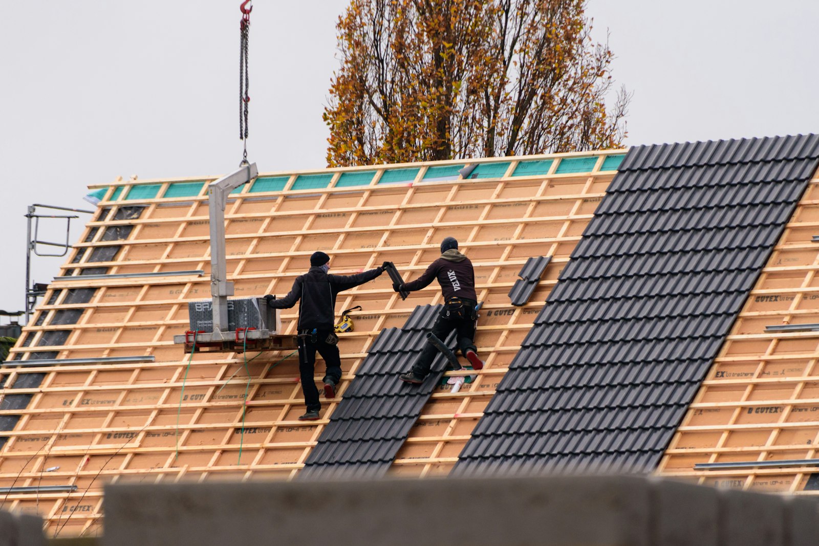 Crew installing new tile roofing on a home under construction